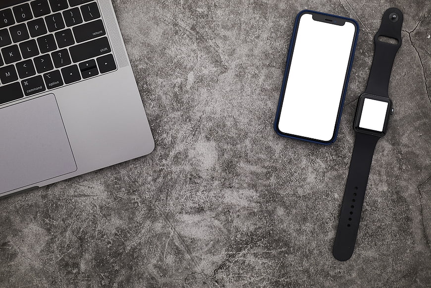 Top view of laptop, smartphone, and smartwatch on concrete background