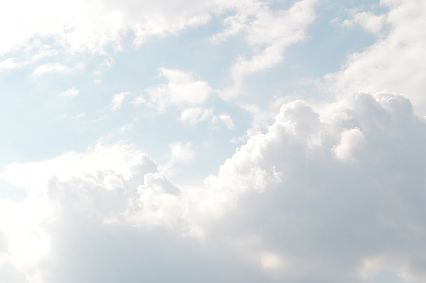 Bright white clouds against a light blue sky background