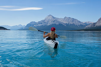 Woman Kayaking on Turquoise Lake with Mountain View