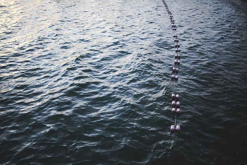Line of pink buoys floating on dark rippling water