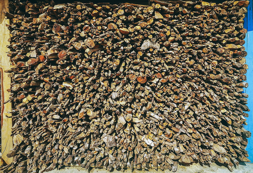 Stack of Firewood Logs Against Blue Wall