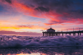 Dramatic Sunset Over Pier With Turbulent Ocean Waves