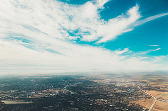 Aerial View of City and River Under Blue Sky with Clouds