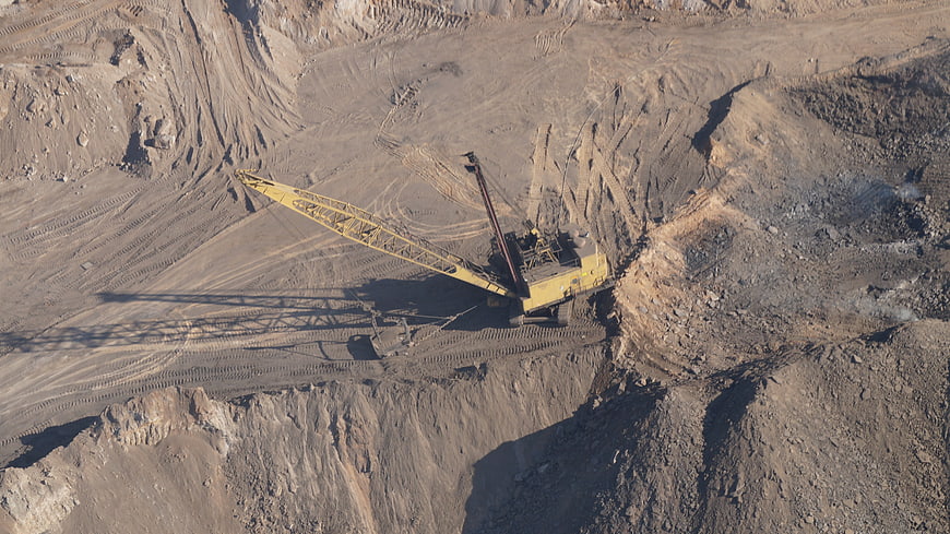 Aerial view of yellow dragline excavator in open pit mine