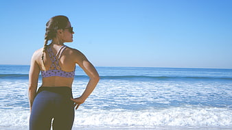 Woman in Sportswear Looking at Ocean on Sunny Beach