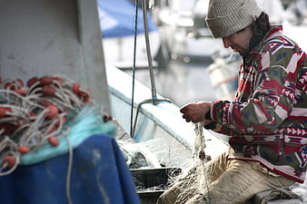 Fisherman Mending Net on Boat in Harbor