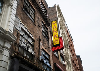 Yellow and Red Neon Parking Sign on Urban Brick Building