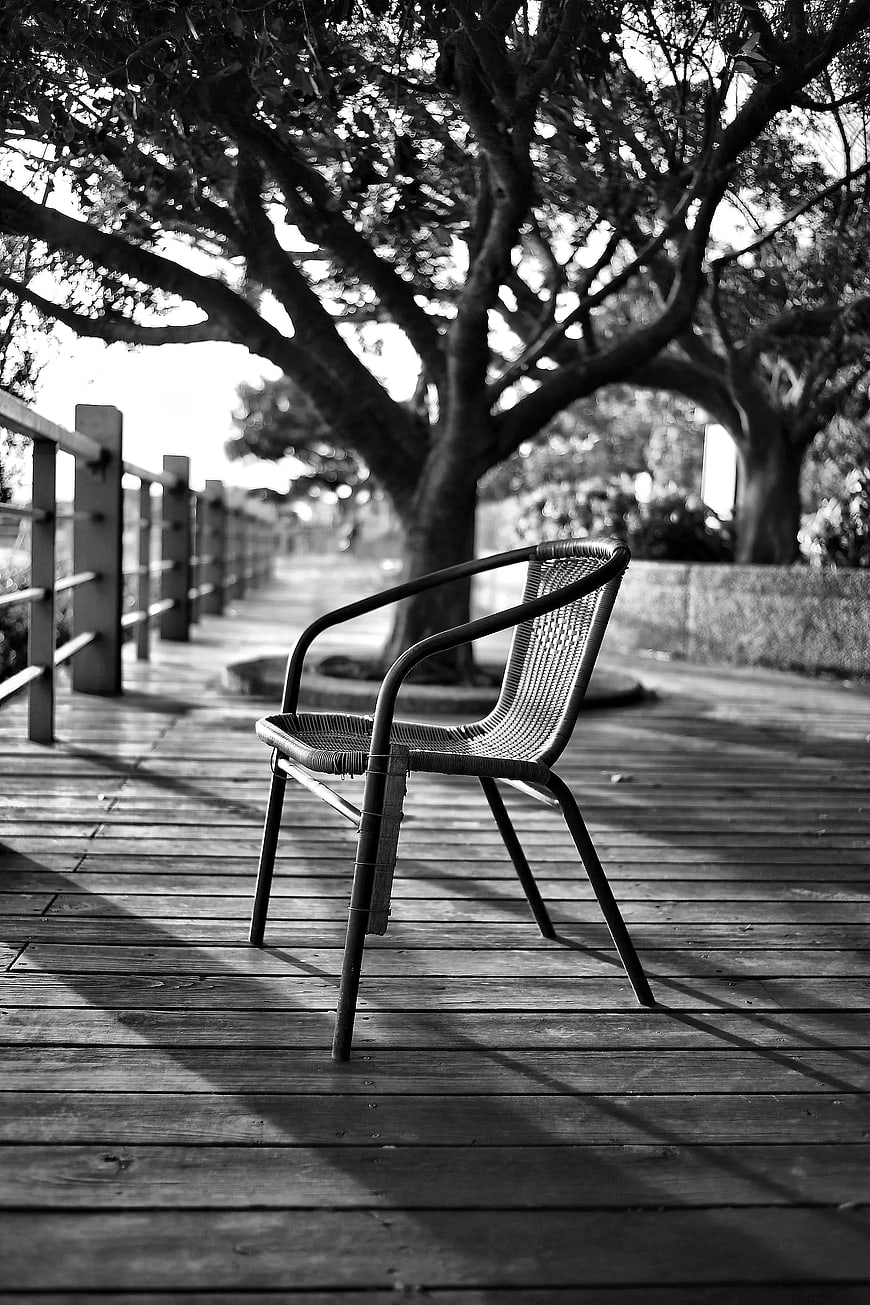 Solitary Wicker Chair on Wooden Deck in Black and White