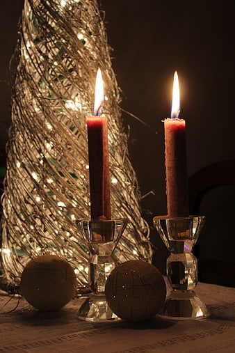 Two lit red candles in crystal holders with rustic twine decoration