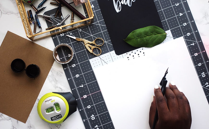 Flat lay of calligraphy tools and workspace with hand writing