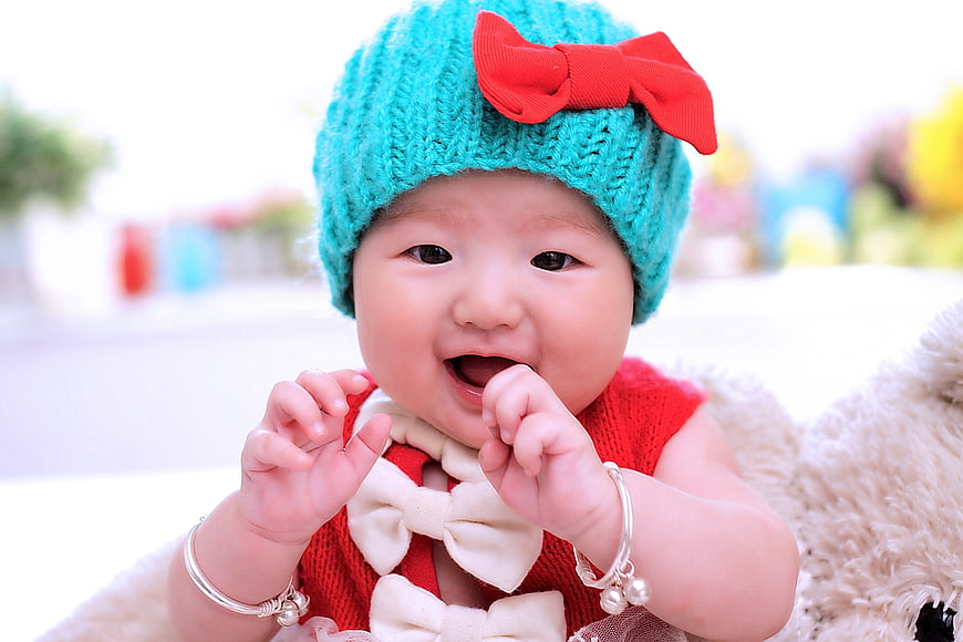 Cute baby girl in turquoise hat and red outfit smiling
