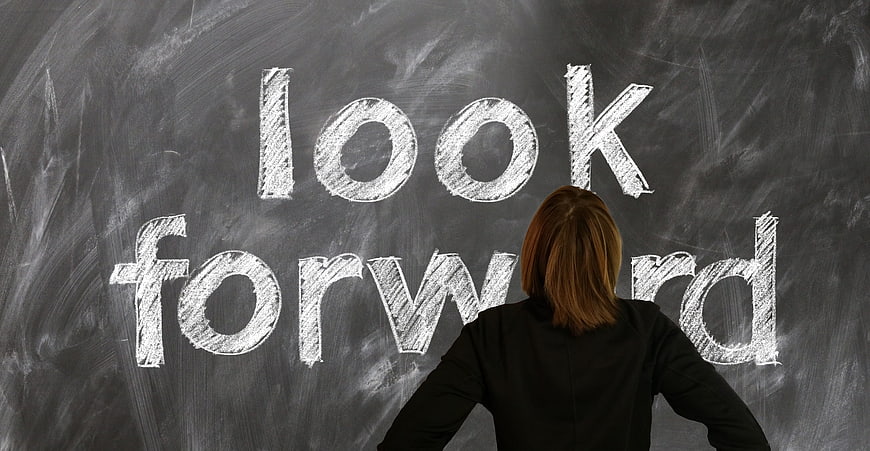 Woman looking at chalkboard with look forward written