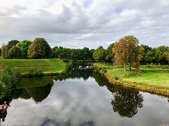 Serene River Landscape with Historic Fortification and Autumn Trees