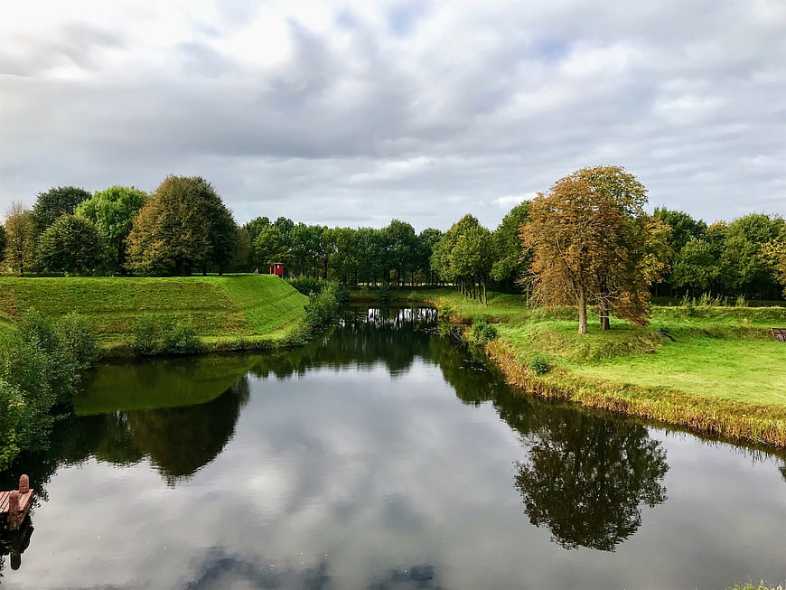 Serene River Landscape with Historic Fortification and Autumn Trees