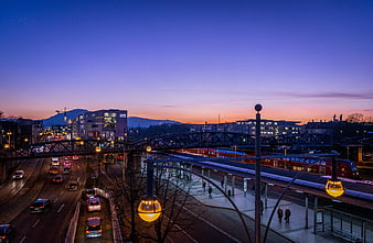 Cityscape at Dusk with Train Station and Highway Traffic