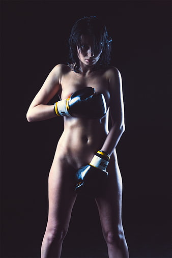 Nude female boxer portrait with black gloves on dark background