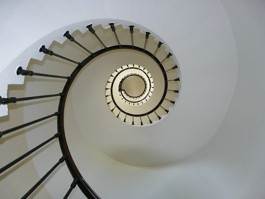 Top-down view of a white spiral staircase with black railing