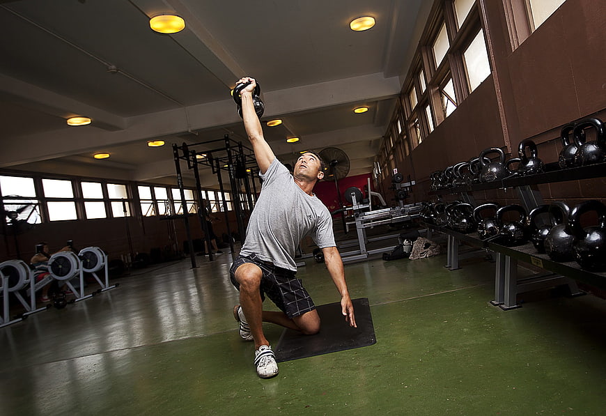 Man performing kettlebell exercise in a commercial gym