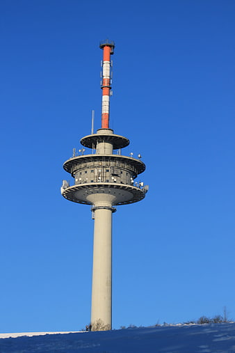 Tall Radio Tower Against Blue Sky in Winter Snow