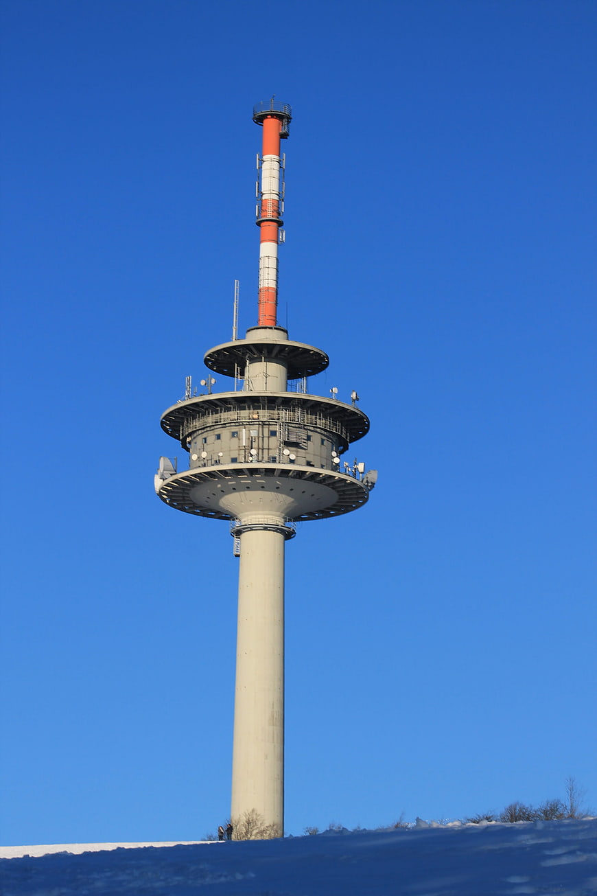 Tall Radio Tower Against Blue Sky in Winter Snow