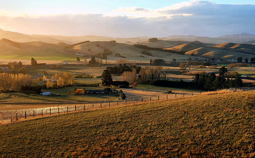 Golden Sunrise Over Rolling Hills and Rural Pasture Landscape
