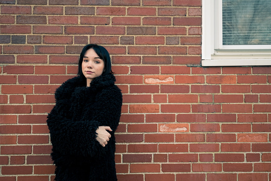 Stylish Woman in Black Coat Against Brick Wall
