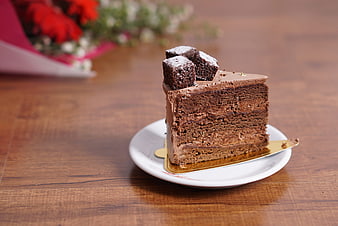 Slice of layered chocolate cake on wooden table