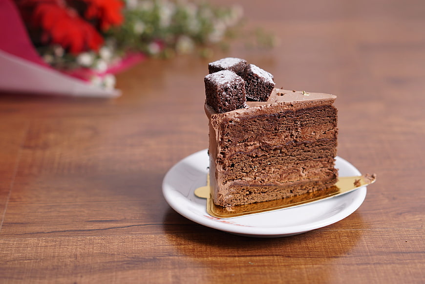 Slice of layered chocolate cake on wooden table