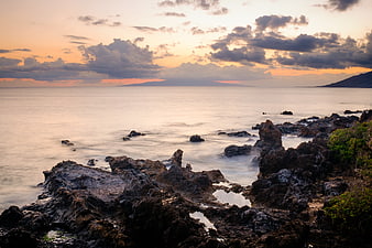Serene Sunset Seascape with Rocky Coastline and Misty Ocean