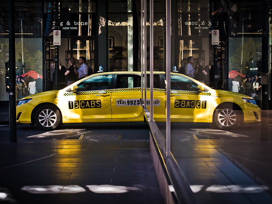Yellow NYC Taxi Reflected in Glass Storefront Window