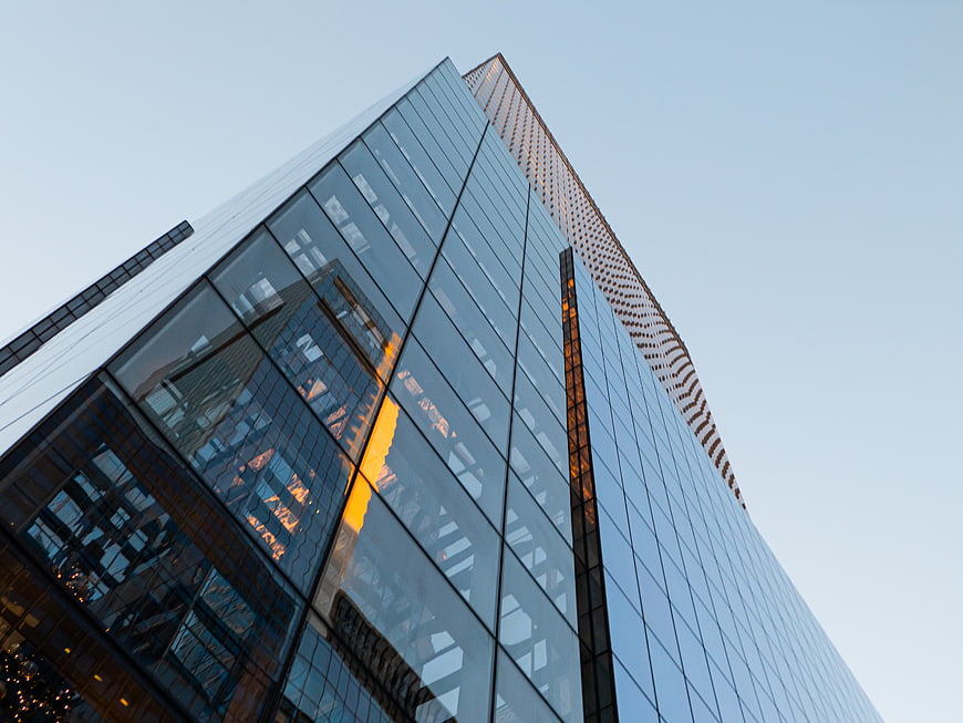Low angle view of modern glass skyscraper with sunset reflection