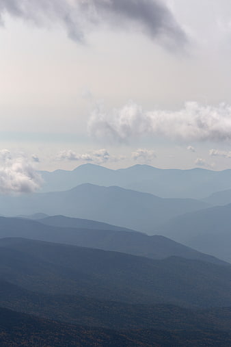 Layered Blue Mountain Ranges with Clouds and Mist