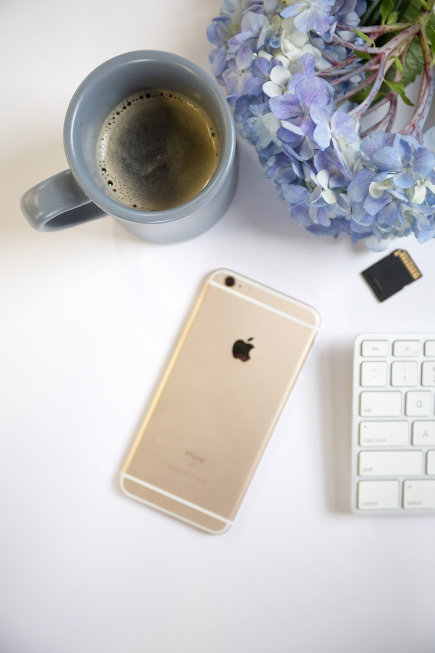 Flat lay workspace with coffee, smartphone, keyboard, and hydrangeas