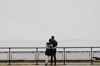 Couple Hugging on Pier Looking at Foggy Sea