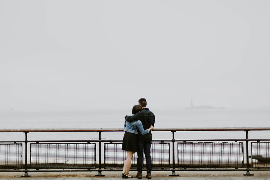 Couple Hugging on Pier Looking at Foggy Sea