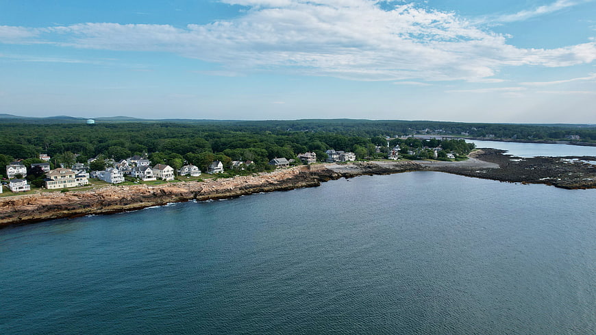 Aerial View of Coastal Town with Rocky Shoreline and Blue Ocean