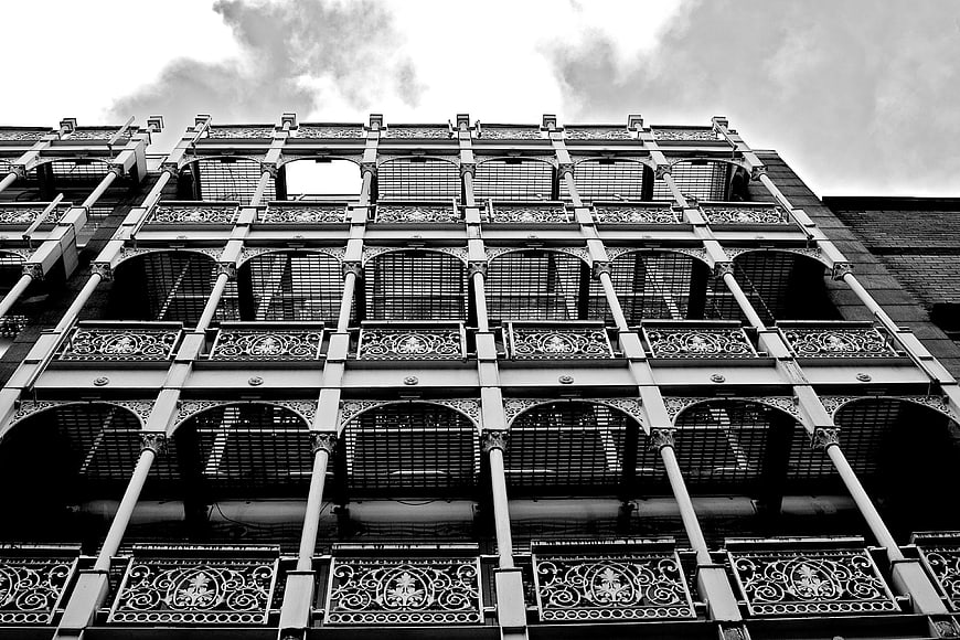 Black and white low angle view of ornate iron fire escape architecture