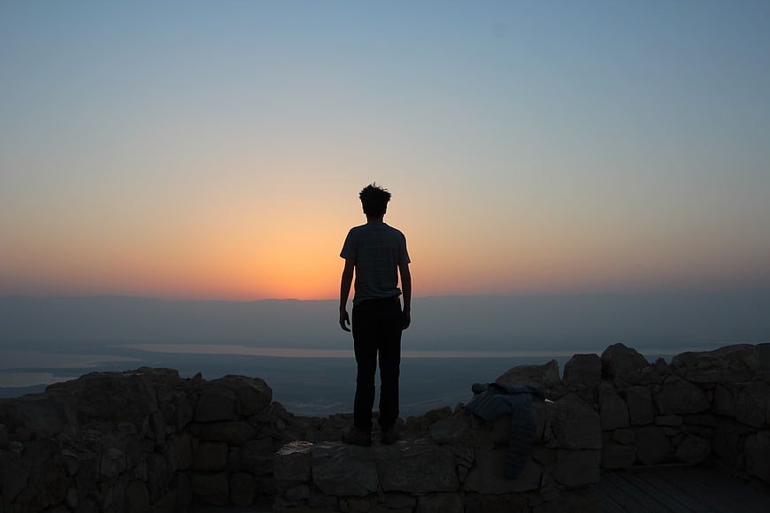 Silhouette of Man Standing on Cliff at Sunset