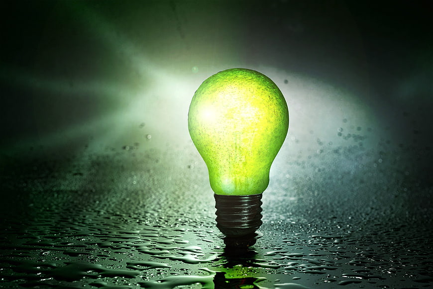 Glowing Green Lightbulb on Wet Surface with Water Drops