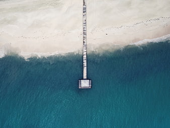 Aerial view of wooden pier extending into turquoise ocean