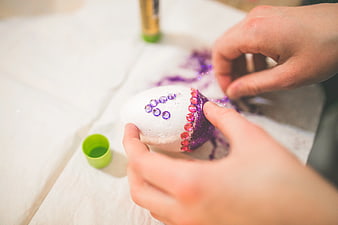 Close up of hands decorating Easter egg with glitter and gems