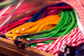 Colorful candy sticks in a wooden bin with tongs
