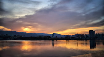Sunset Reflection on River with City Skyline and Mountains