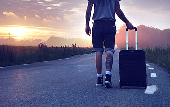 Man Walking Down Road with Suitcase at Sunset