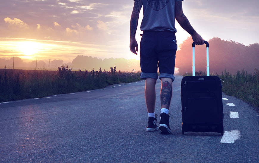 Man Walking Down Road with Suitcase at Sunset
