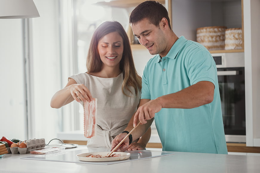Happy couple cooking breakfast together in modern kitchen