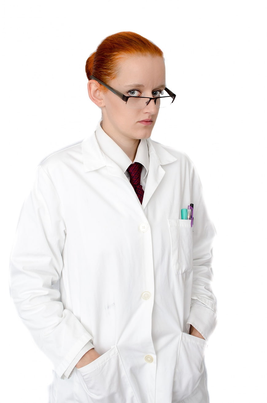 Serious female doctor in white lab coat with glasses