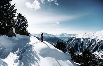 Lone Hiker Standing on Snowy Mountain Ridge Overlooking Peaks