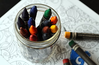 Colorful Crayons In Glass Jar On Adult Coloring Book