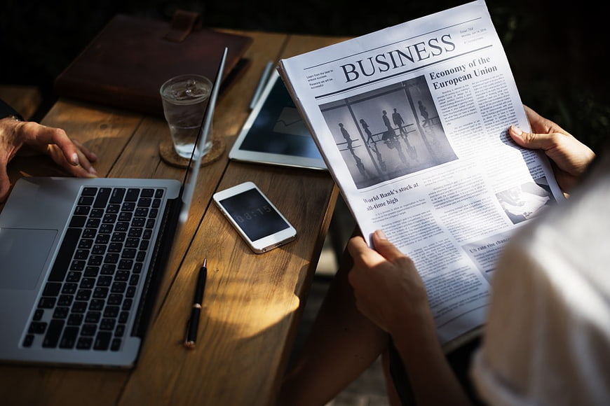 Business Meeting with Laptop and Newspaper on Wooden Table